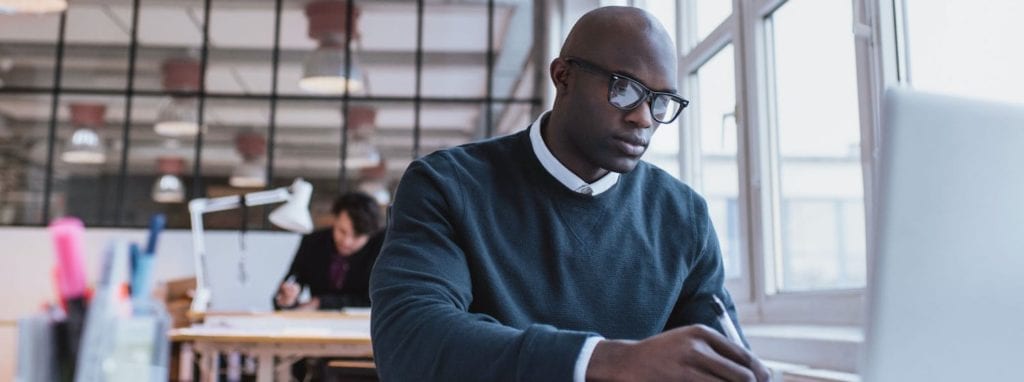 Man sitting in office space working on laptop